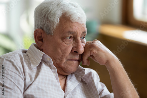 Sad grandfather put head on hand lost in thoughts