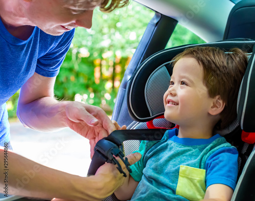 Toddler boy buckled into his car seat by his father