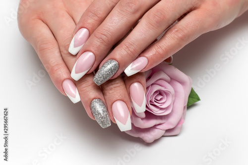 Wedding sharp French manicure with silver sequins on the ring fingers on a white background close-up on long nails with a pink rose in hand