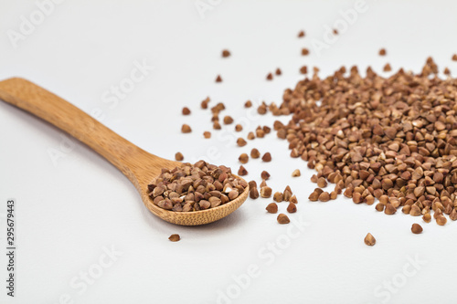 buckwheat in a plate on a white table and in a wooden spoon