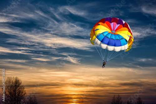 People are gliding with a parachute on the background of sunset.