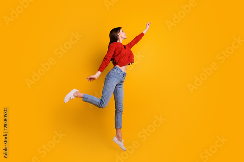 Full length photo of positive cheerful lovely girl jump hold hand want catch her flying parasol star wear good looking clothing isolated over yellow color background