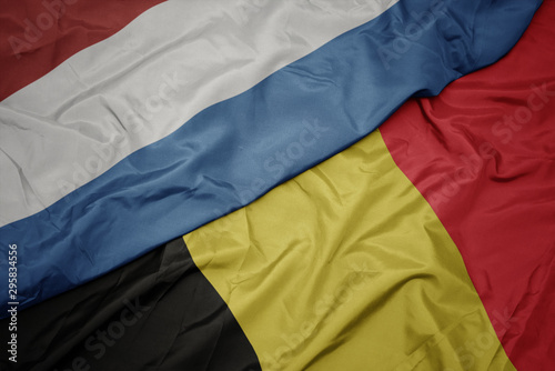 waving colorful flag of belgium and national flag of luxembourg.