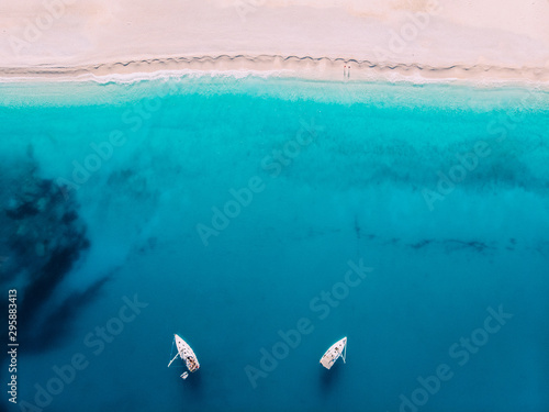 Aerial top down view two yachts stand at sea near white sandy beach