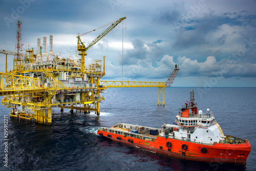 The shipping box is loaded from an offshore oil rig to the supply vessel at sunset.