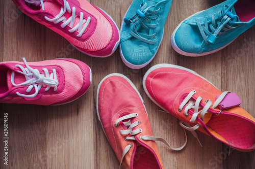 Three pairs of colorful sneakers on a wooden background.