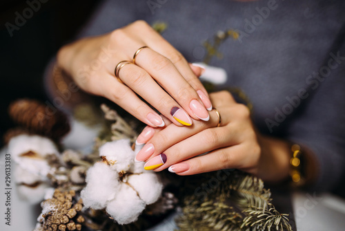 French manicure. Manicure closeup nail design. Christmas manicure on a background of cotton and Christmas tree twigs