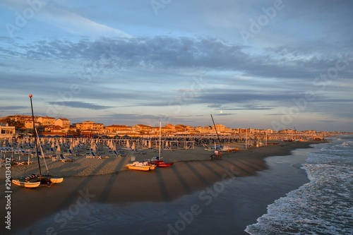 Scenic view of the beach of Lido di Camaiore at sunset with the cityscape in the background, Versilia, Tuscany, Italy