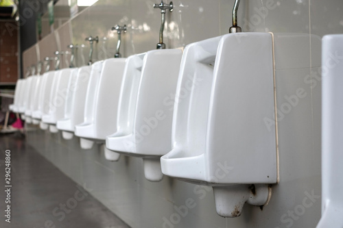 Empty perspective row of white porcelain urinals in line outdoor.