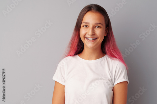 Young girl teenager with pink hair happy and smiling over gray background