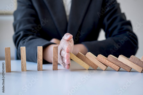 Risk and Strategy in Business, Image of hand stopping falling collapse wooden block dominoes effect from continuous toppled block, prevention and development to stability