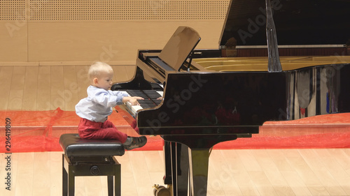 Little child playing at big piano in concert hall, early artistic education