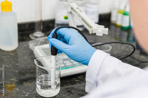 Woman hands performing pH test on pH meter electronic instrument