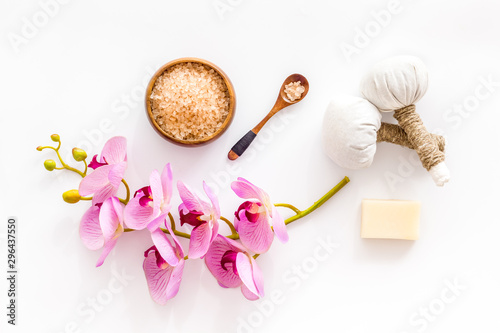 Massage table with thai herbal balls and orchids on white background top view pattern