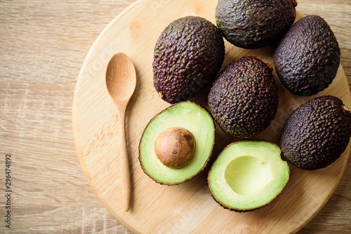 Ripe hass avocado fruit with spoon on wooden plate