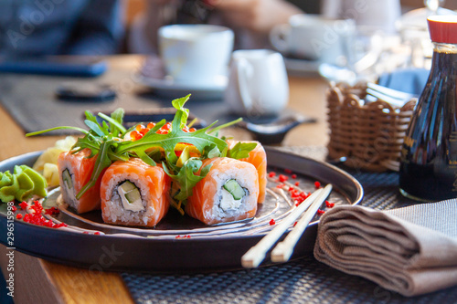 Sushi roll japońskie jedzenie w restauracji. Zestaw California Sushi Roll z łososiem, warzywami, ikrą. Sushi z pałeczkami. Japońskie menu restauracji