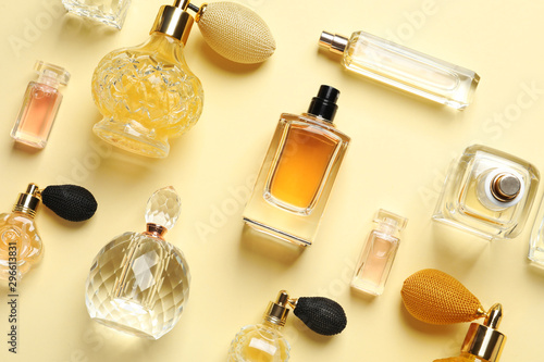 Flat lay composition with different perfume bottles on light yellow background