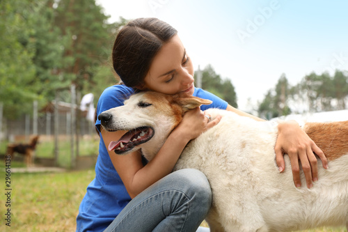 Female volunteer with homeless dog at animal shelter outdoors