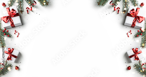 Creative frame made of Christmas fir branches, gift boxes, red decoration, sparkles and confetti on white background. Xmas and New Year holiday, bokeh, light. Flat lay, top view