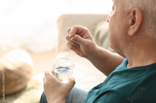 Elderly man taking medicine at home
