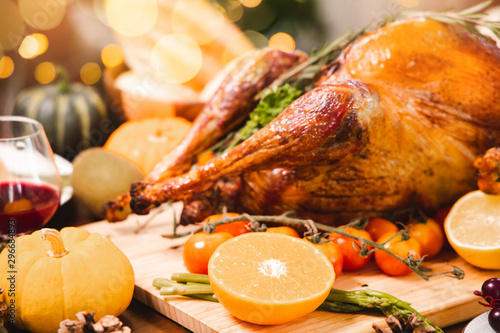 Roasted chicken or turkey with sauce and grilled autumn vegetables: corn,pumpkin on wooden table, top view, frame. Christmas or Thanksgiving Day food concept.