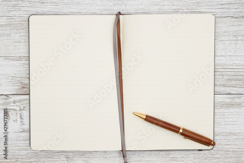 Blank brown journal with pen on a weathered whitewash wood background