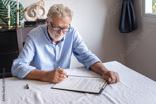 Senior old man elderly examining and signing last will and testament