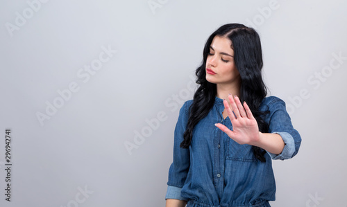 Young woman making a rejection pose on a gray background