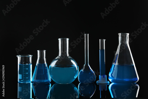 Laboratory glassware with blue liquids on black background