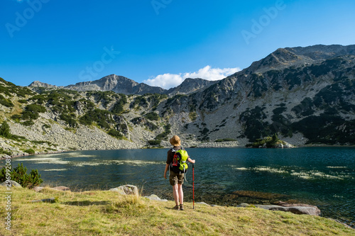 Young woman with backpack hiking in the mountains near beautiful lake 