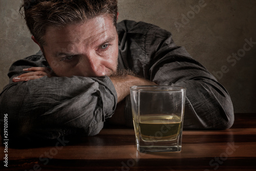 desperate alcoholic man . depressed addict isolated in front of whiskey glass trying not drinking in dramatic expression suffering alcoholism and alcohol addiction problem