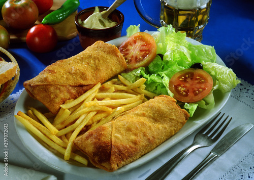 Bandeja con dos empanadillas al horno, patatas fritas y ensalada.