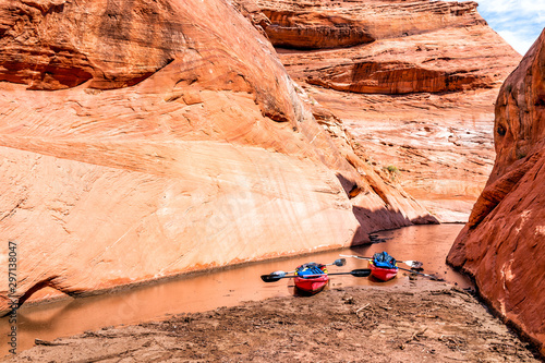 Kayaks by trailhead of hiking trail in Lake Powell narrow and shallow antelope canyon with dirty muddy water and rock formations