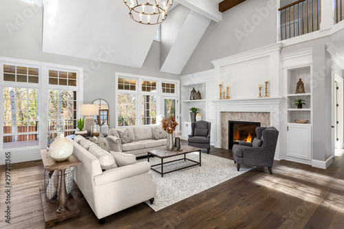 Beautiful living room in new traditional style luxury home. Features vaulted ceilings, fireplace with roaring fire, and elegant furnishings.