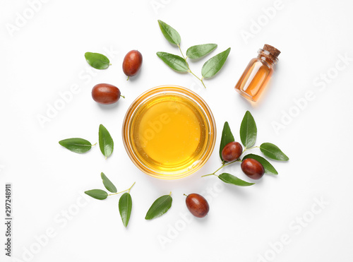 Bowl with jojoba oil and seeds on white background, top view