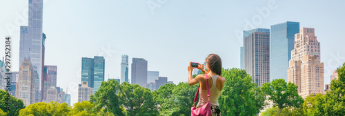 New York City tourist taking photo with phone of NYC Skyline of skyscrapers buildings towers in summer travel vacation panoramic banner background.