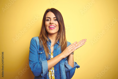 Young beautiful woman standing over yellow isolated background clapping and applauding happy and joyful, smiling proud hands together