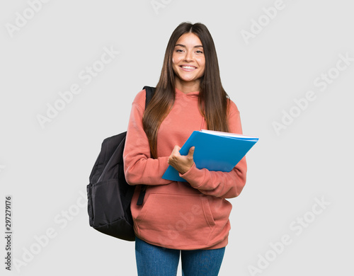Young student woman holding notebooks keeping the arms crossed in frontal position over isolated grey background
