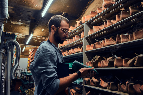 Young shoemaker is searching for special shoe form for his new project.