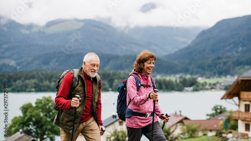 Senior pensioner couple with nordic walking poles hiking in nature.