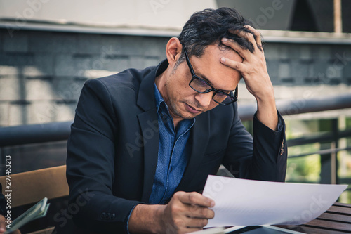 Senior businessmen are worried about the work and the economic downturn. Tired and worried business man at workplace in office holding his head on hands.