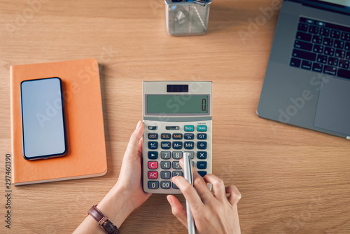 Woman holding and press calculator to calculate income expenses and plans for spending money on home office.