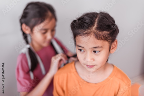 Asian elder sister are making braids for her young sister.