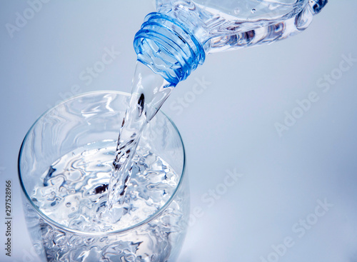 agua cayendo desde la botella a un vaso con fondo azul
