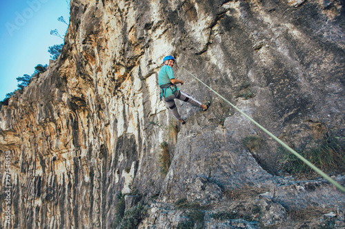 Senior man with a rope climbing on the rock.