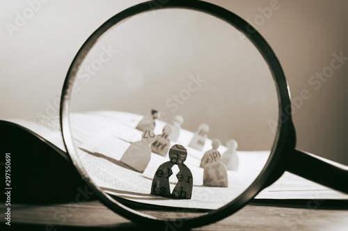 Business recruitment or hiring photo concept. Looking for talent. Icons of candidates are standing on open newspaper under magnifier.