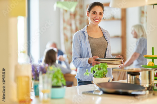 Lächelnde Hausfrau trägt Teller in der Küche
