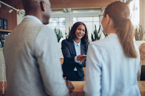 Smiling African American hotel concierge helping guests during c