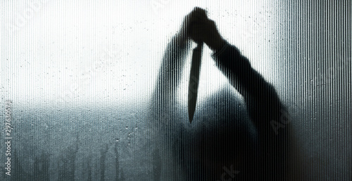 Silhouette of murderer or robber with big knife in hand behind Frosted glass in the bathroom background,concept of scary crime scene of horror or thriller movies,Halloween theme
