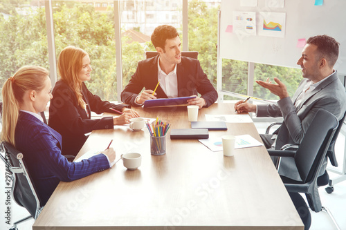 Group of business people discussing business in a meeting room with one empty chair.